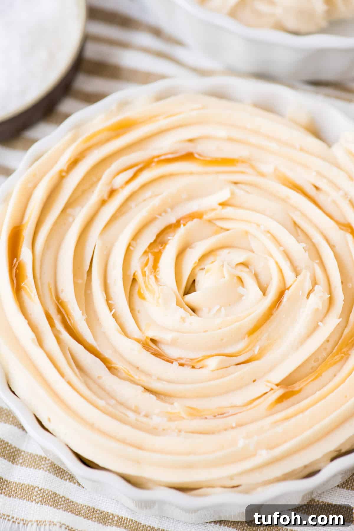 Silky Salted Caramel Frosting Recipe for Cakes & Cupcakes 5 salted caramel frosting with caramel sauce swirled in white bowl