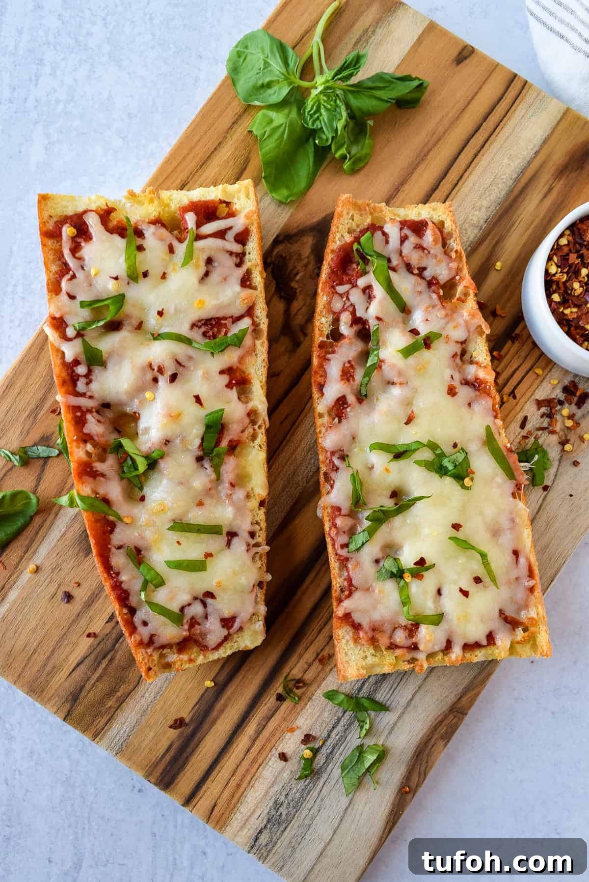 Crispy French Bread Pizza Made in the Air Fryer 2 Air Fryer French Bread Pizza on a cutting board topped with basil.