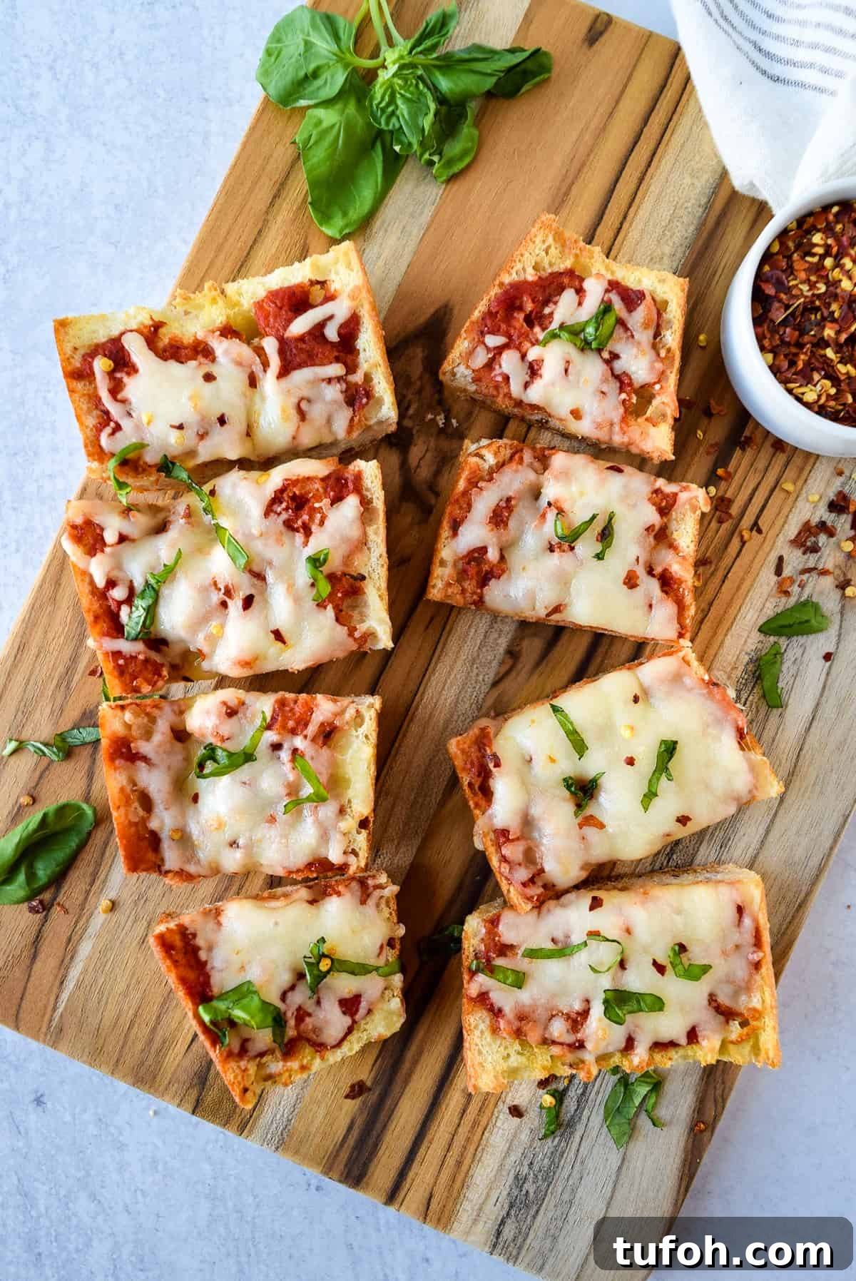 Crispy French Bread Pizza Made in the Air Fryer 3 Air Fryer French Bread Pizza cut into 8 pieces on a cutting board.