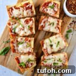 Air fryer french bread pizza cut into slices on a cutting board.