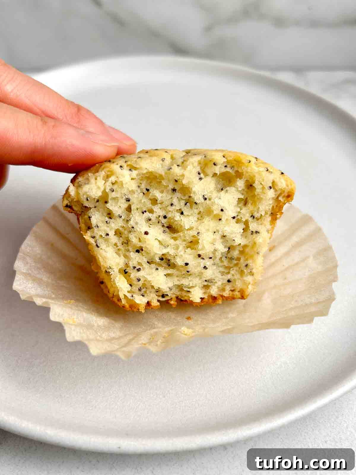 Lemon Poppy Seed Muffins Recipe: Moist, Zesty Muffins in 30 Minutes 9 muffin with piece taken out of it to show the crumb.