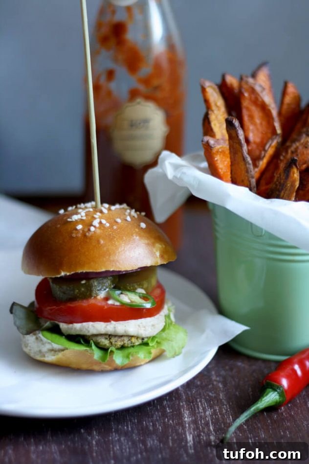 Juicy vegan falafel burger in a pretzel bun served with creamy tahini sauce and crispy and tender sweet potato fries. The best healthy falafel burger I've ever had!