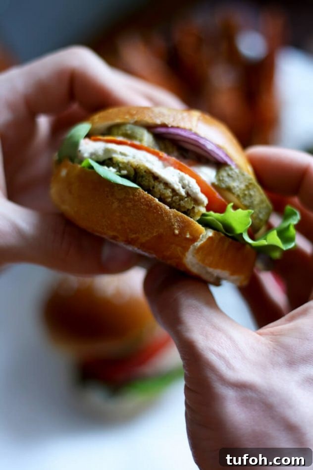 Juicy vegan falafel burger in a pretzel bun served with creamy tahini sauce and crispy and tender sweet potato fries. The best healthy falafel burger I've ever had!