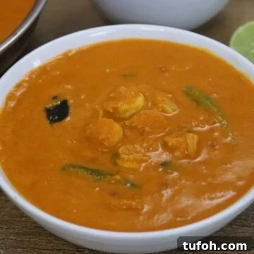 goan prawn curry recipe served in a white bowl with steamed rice and a lemon slice.
