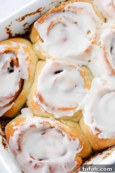 Flaky Apple Cinnamon Rolls with Brown Sugar Glaze 8 Sourdough Cinnamon Rolls Iced in white dish.