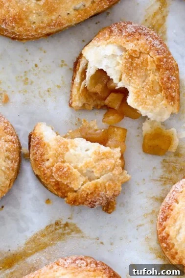 Flaky Apple Cinnamon Rolls with Brown Sugar Glaze 9 apple hand pie broken open on parchment paper.