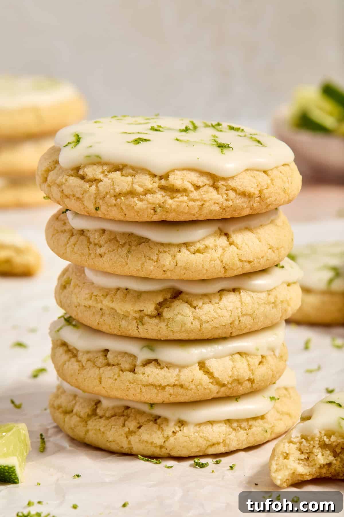 Stack of key lime cookies with lime icing on surface.