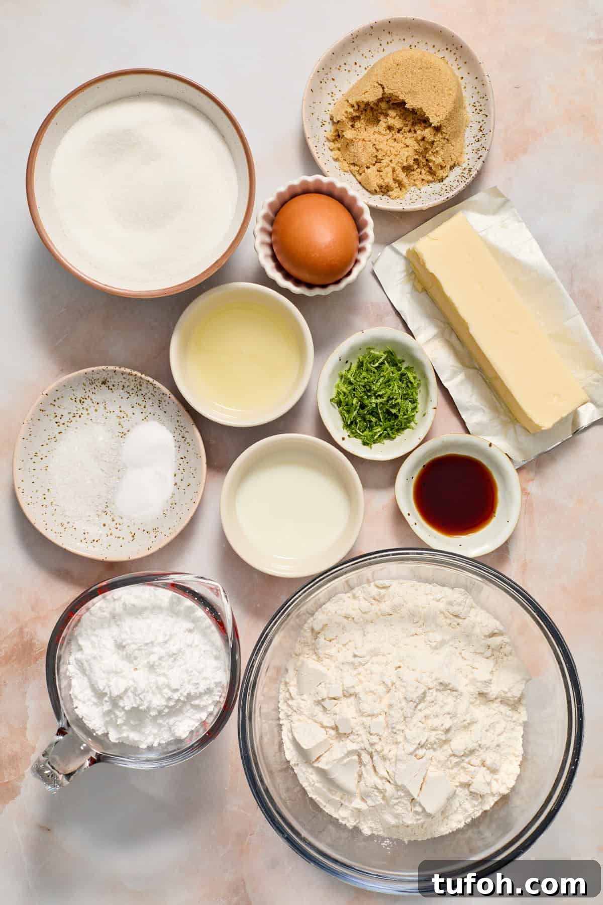 Butter, flour, sugar, vanilla, lime zest and other ingredients arranged on surface.