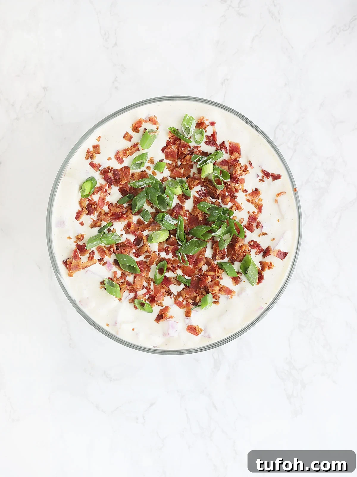 top of cornbread salad covered with ranch dressing, bacon and sliced green onions