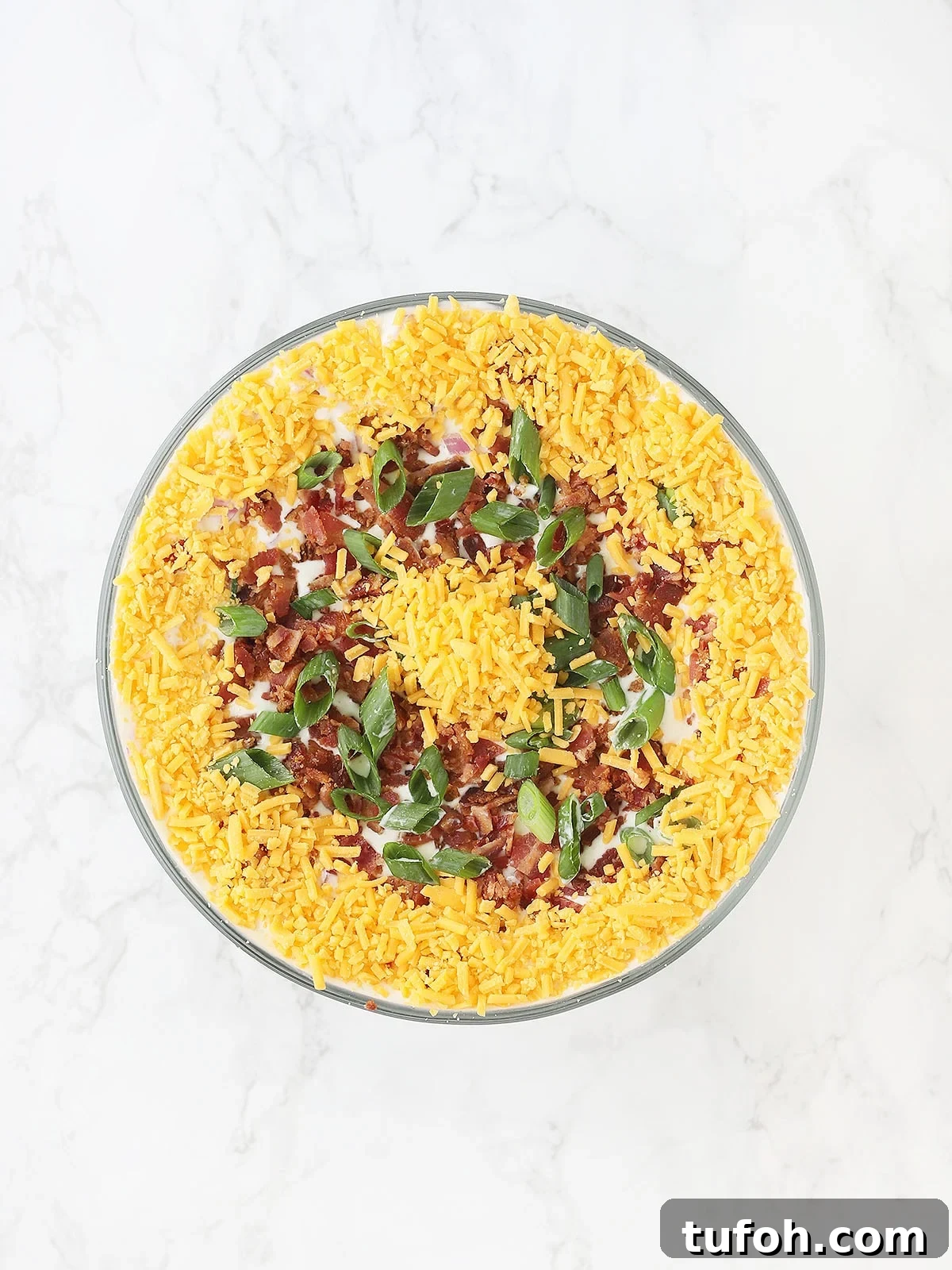 top of cornbread salad covered with bacon, green onions and shredded cheese