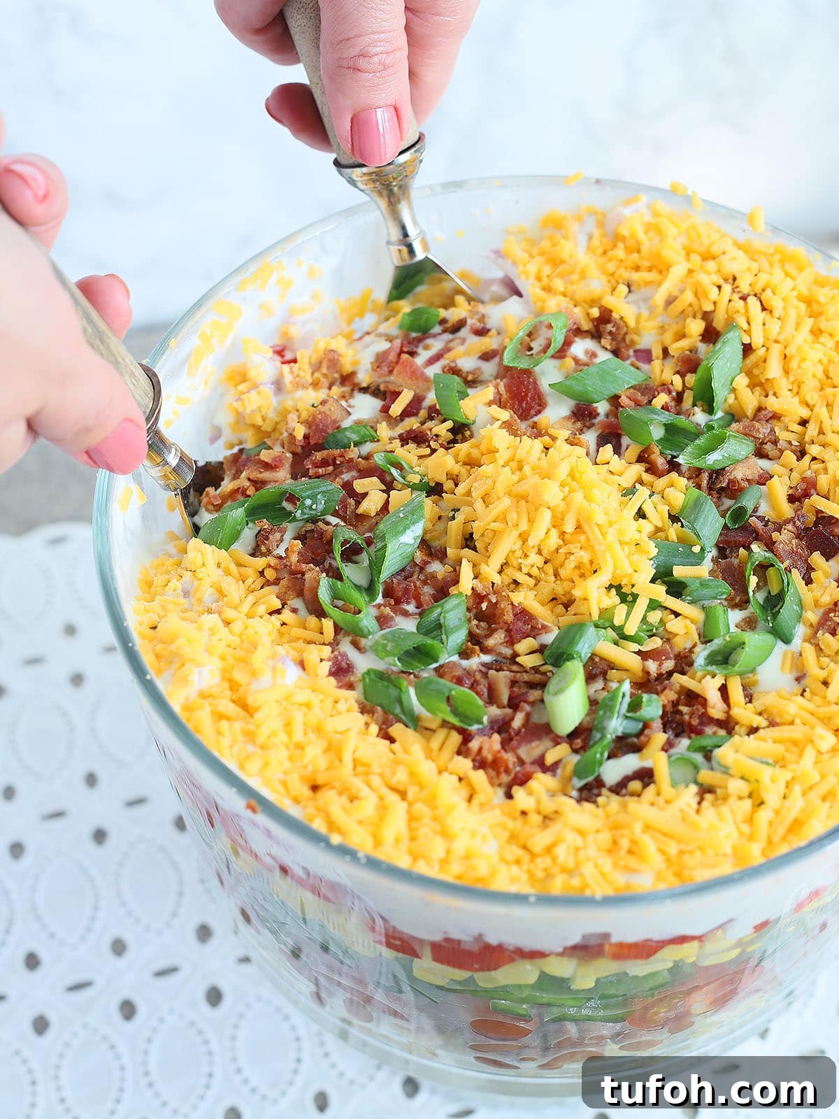 hands using salad tongs to serve the cornbread salad