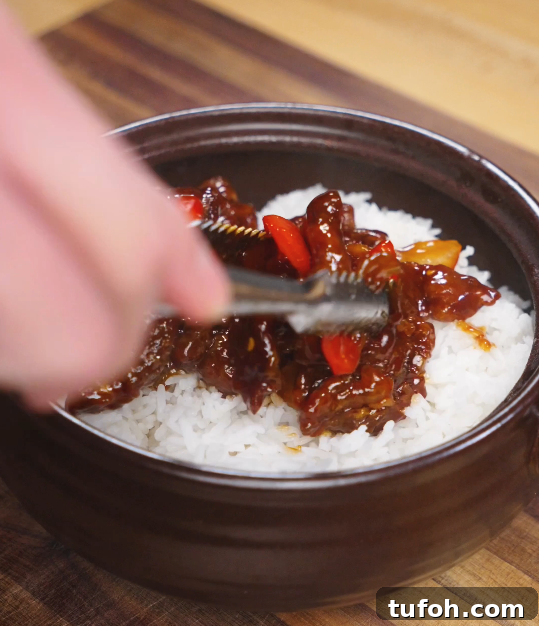 Beijing-Style Beef Stir-Fry Recipe 10 Golden brown crispy beef pieces resting in a skimmer above hot oil, fresh from deep frying for the Beijing Beef.