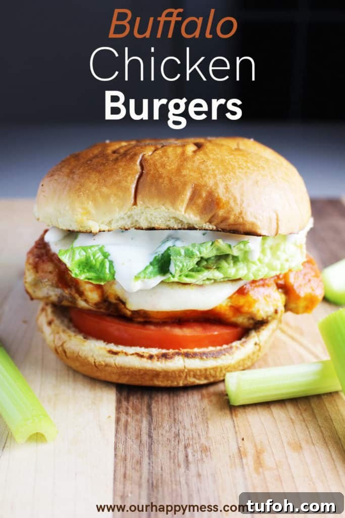 Buffalo Chicken Burgers with Tangy Blue Cheese Slaw 7 A Buffalo chicken burger with cheese, ranch, tomato and lettuce on a wooden cutting board