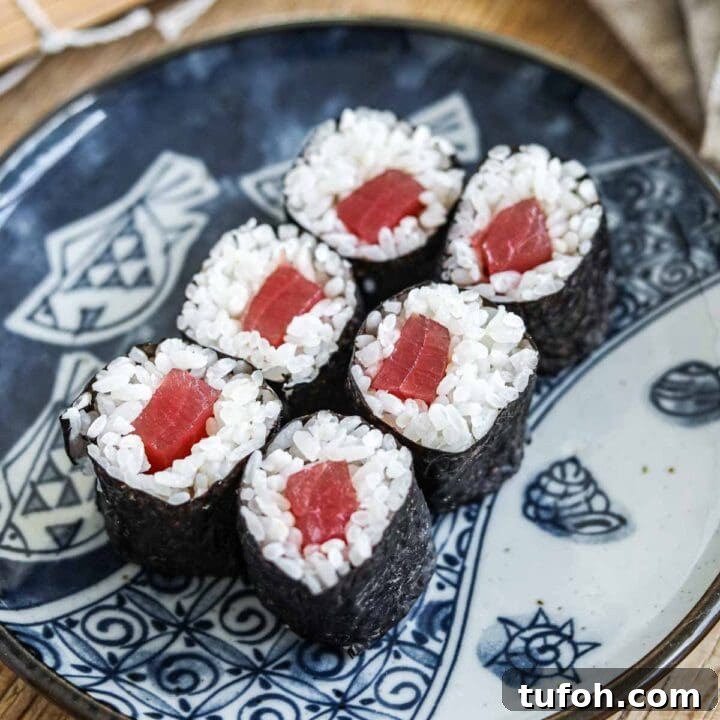 Tekka maki (tuna sushi roll) on a blue Japanese ceramic plate with a bamboo sushi mat.