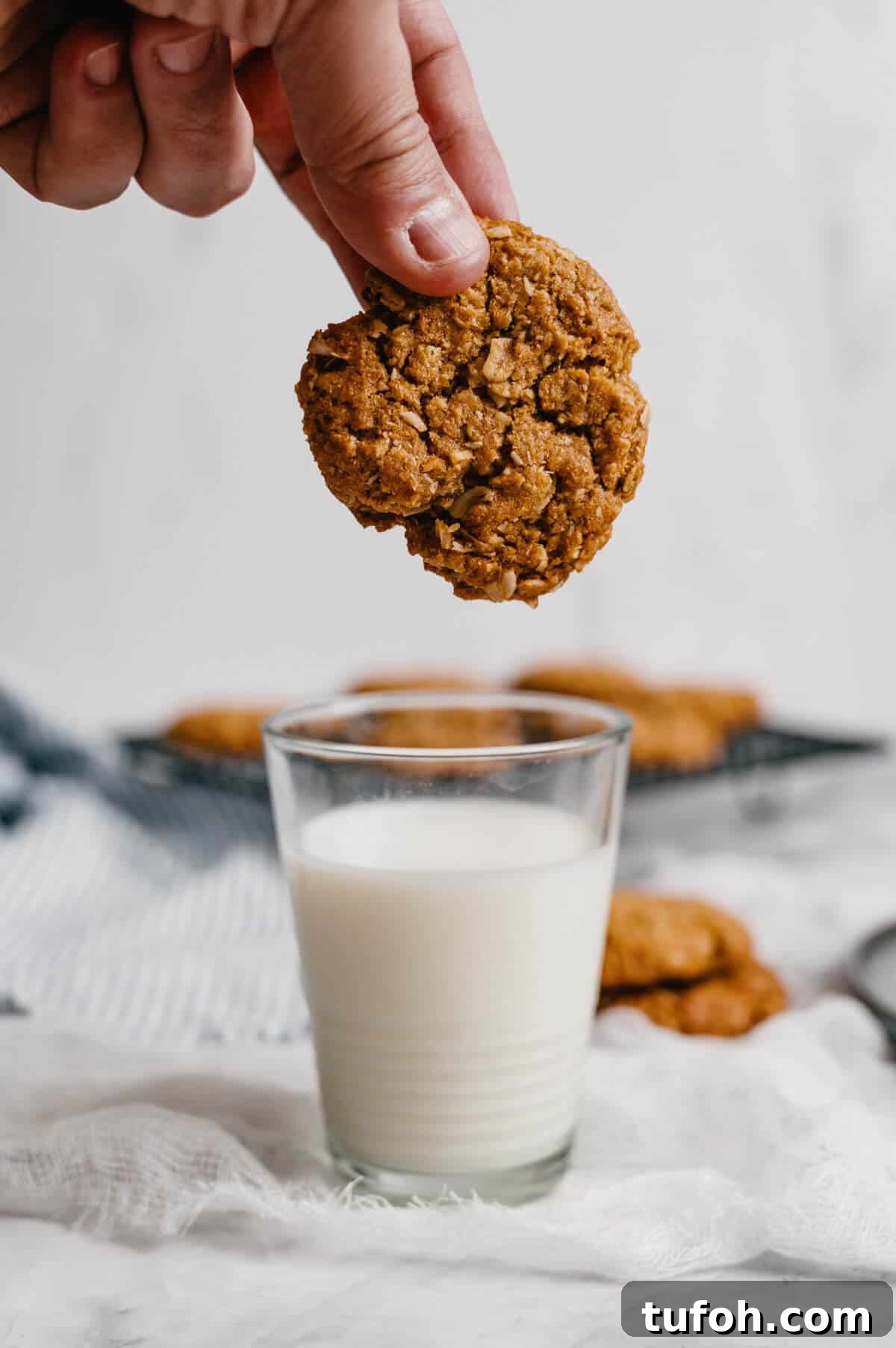 dipping an Anzac biscuit into a glass of milk.