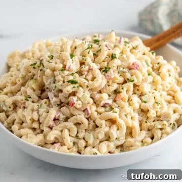 A creamy classic macaroni salad in a large white bowl.