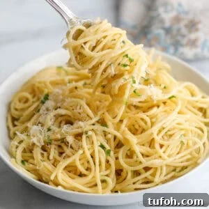 Pasta twirled around a fork and in a large white bowl.