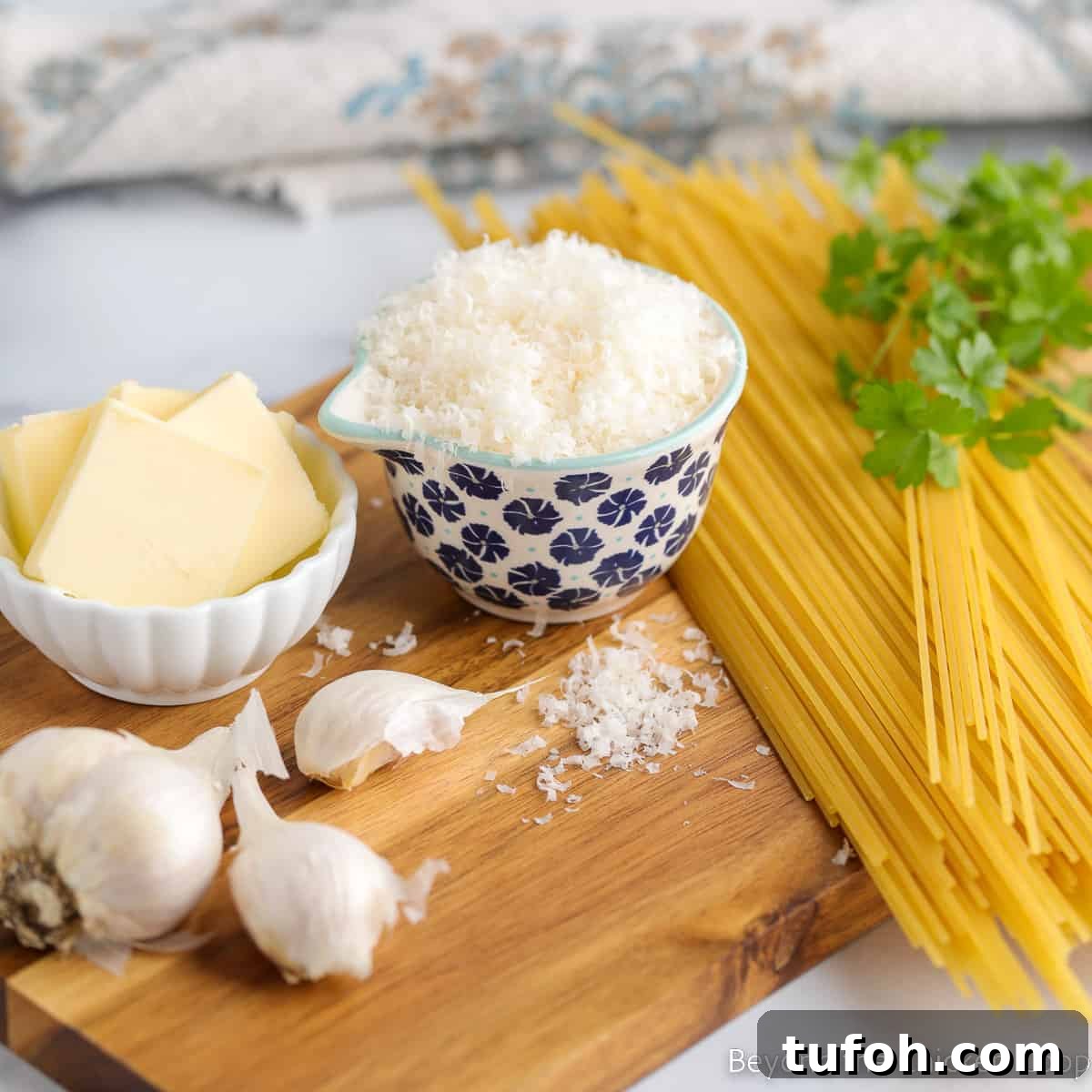 Spaghetti noodles next to a bowl of parmesan and butter. 