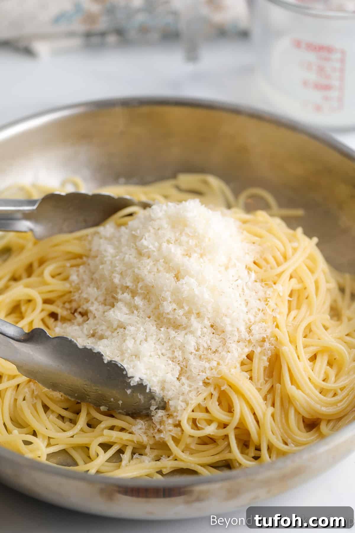 Shredded parmesan cheese on pasta in a pan. 