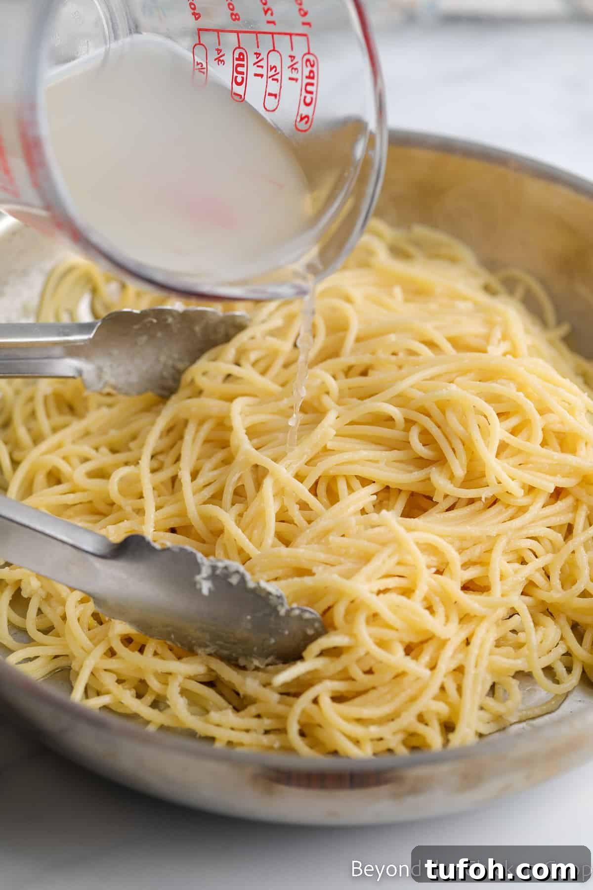 Adding pasta water to spaghetti.