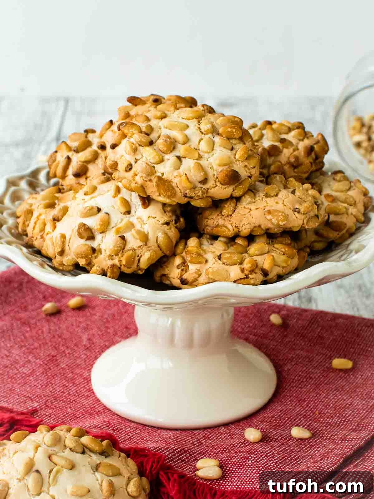Pignoli Cookies: Classic Italian Almond Macaroon Recipe 2 Pignoli Cookies on a white plate with a stand.