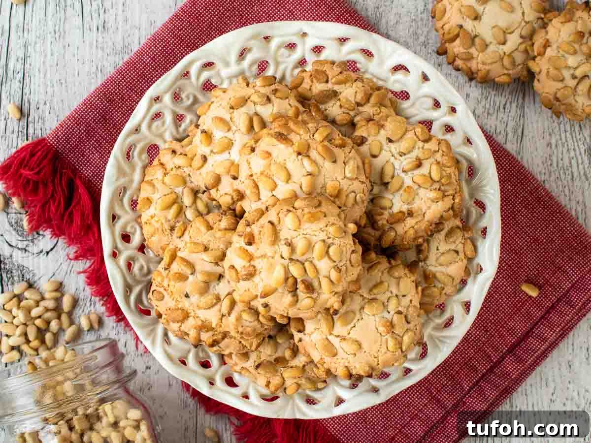Pignoli Cookies: Classic Italian Almond Macaroon Recipe 9 Cookies coated in pine nuts on white plate viewed from above.