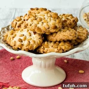 Pignoli Cookies: Classic Italian Almond Macaroon Recipe 10 Pignoli Cookies on a white plate with a stand.