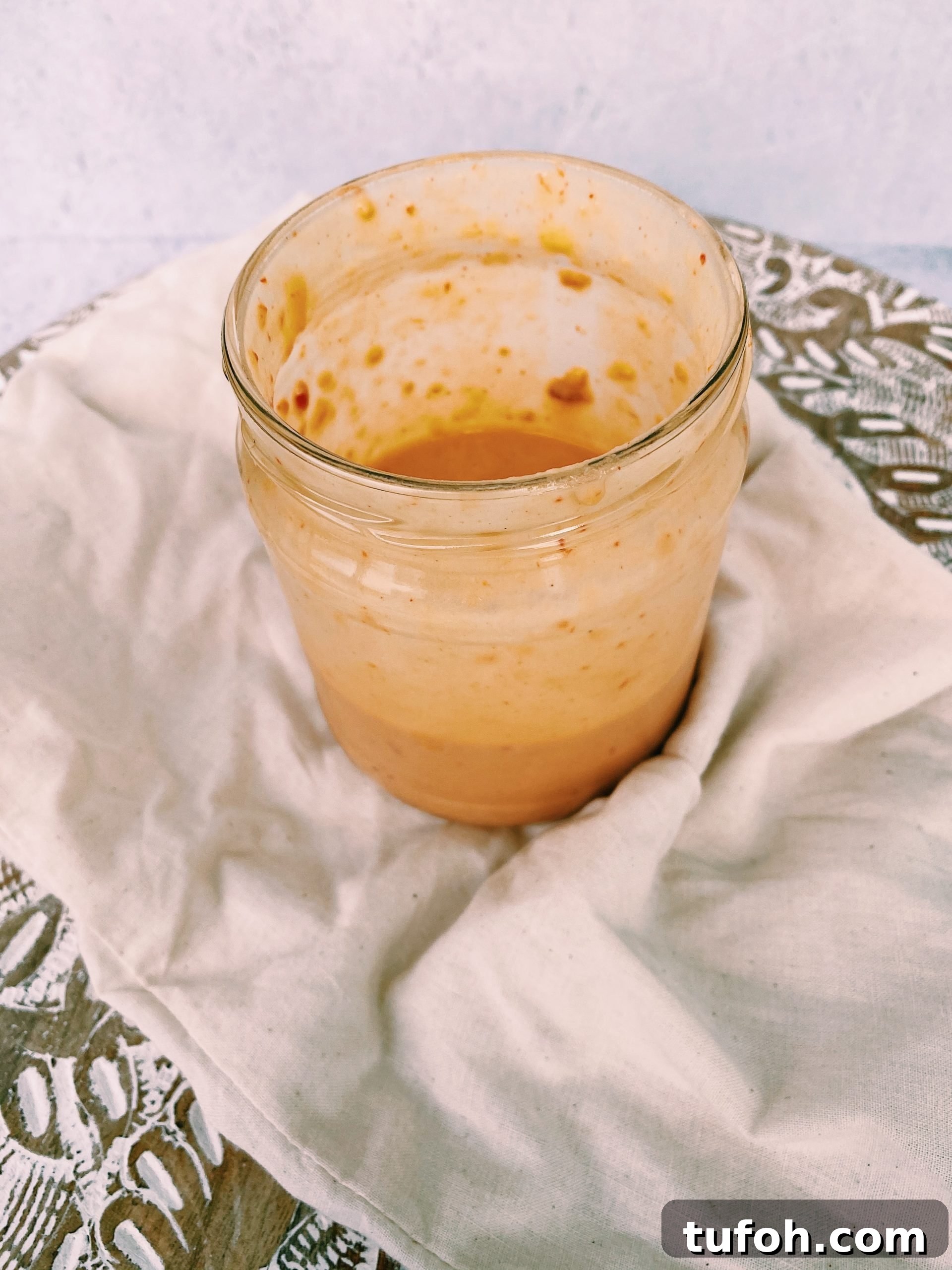half full mason jar of hummus salad dressing on white tea towel.