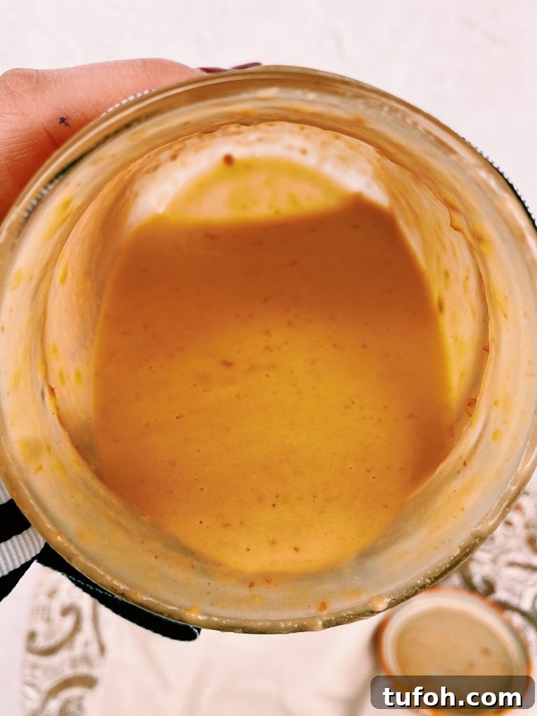 hummus dressing pouring out of mason jar, hand holding it