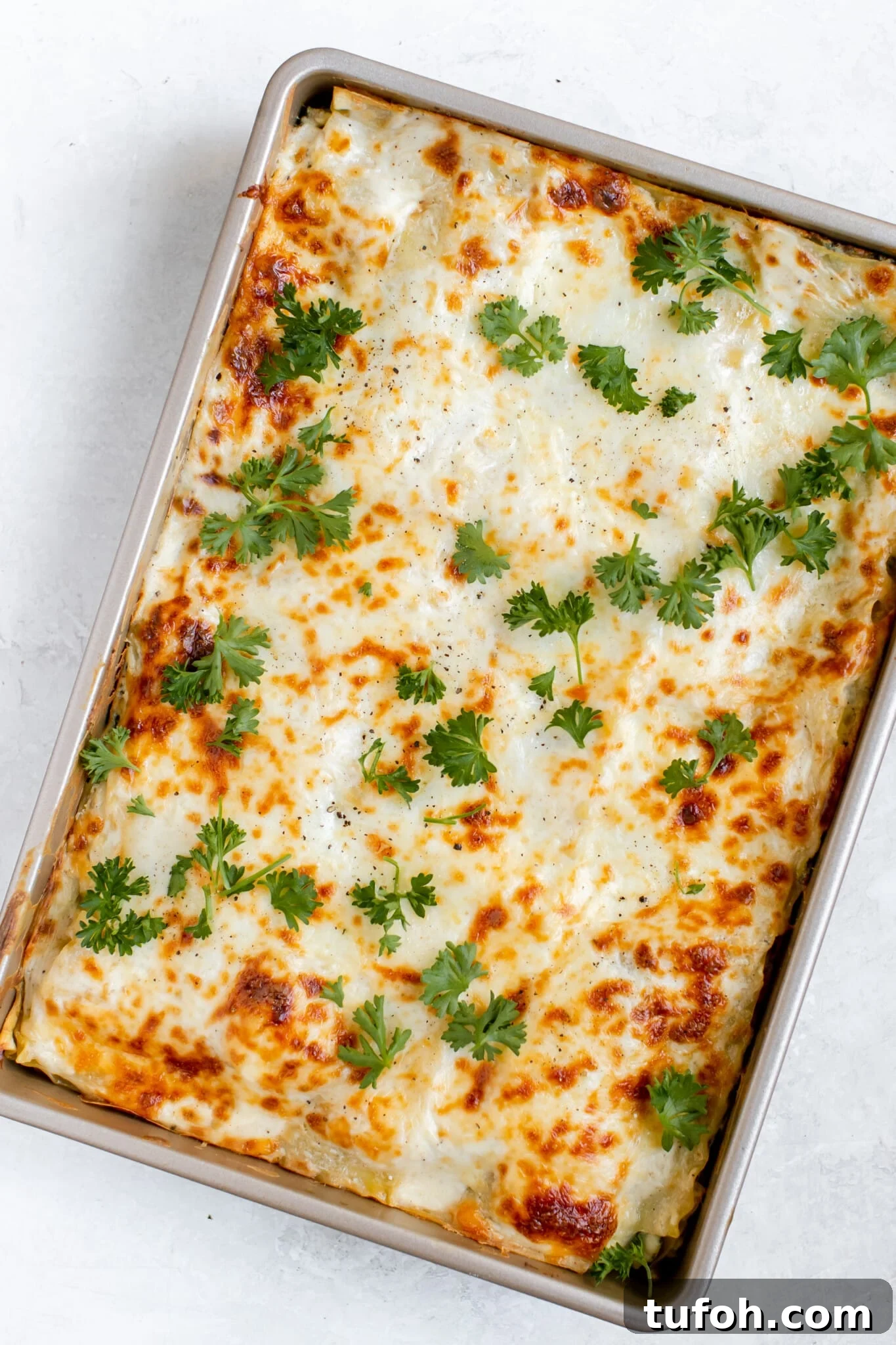 lasagna in a 9x13 pan with melted cheese and parsley on top