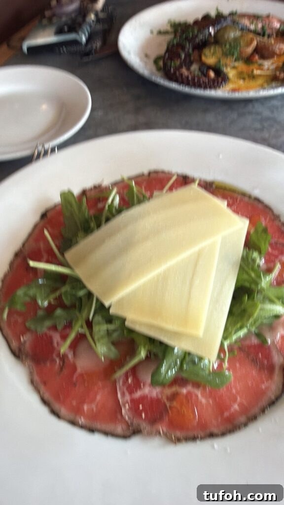 Wagyu been topped with greens, dressing, and cheese