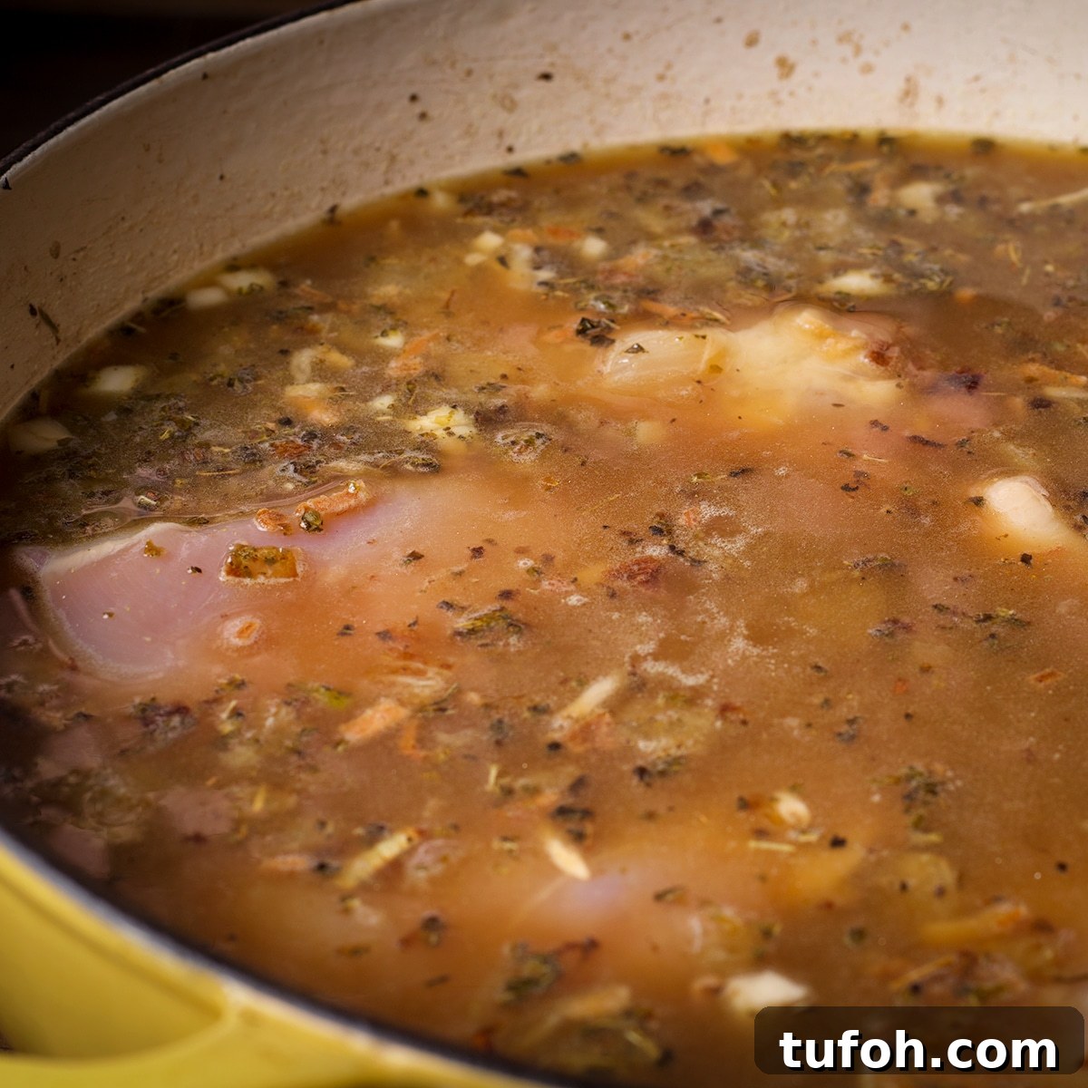 Creamy Mushroom Chicken with Parmesan Rice Bowl 8 A sauce pan filled with cooked onions, garlic and spices, chicken broth and pieces of boneless, skinless chicken breasts.