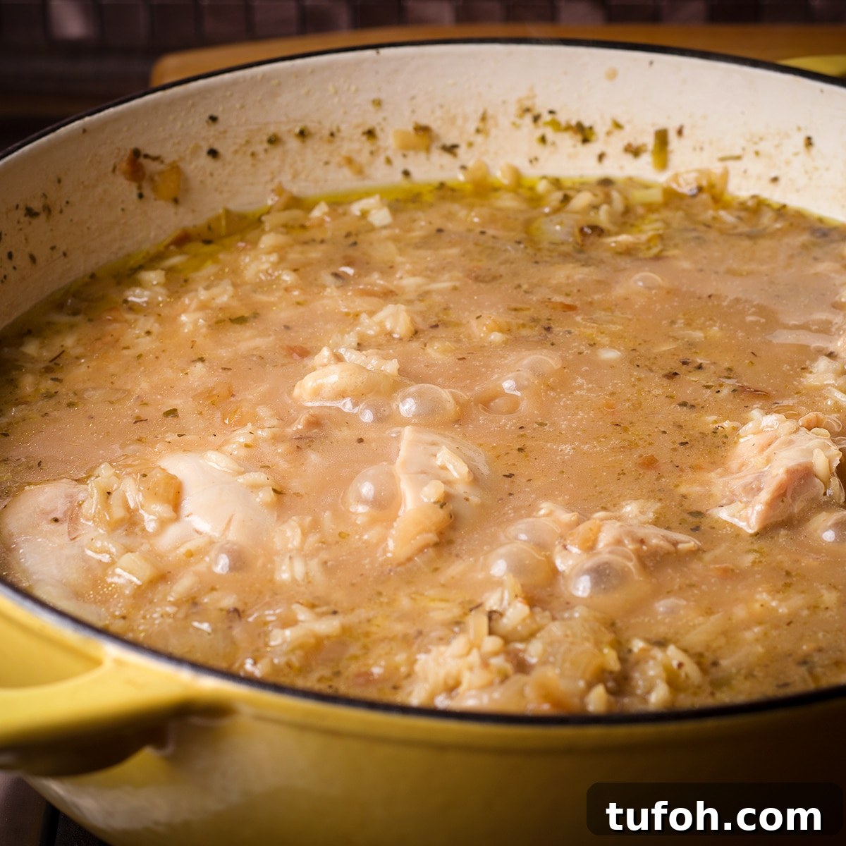 Creamy Mushroom Chicken with Parmesan Rice Bowl 9 A pan filled with chicken and rice that have been cooked in chicken broth.