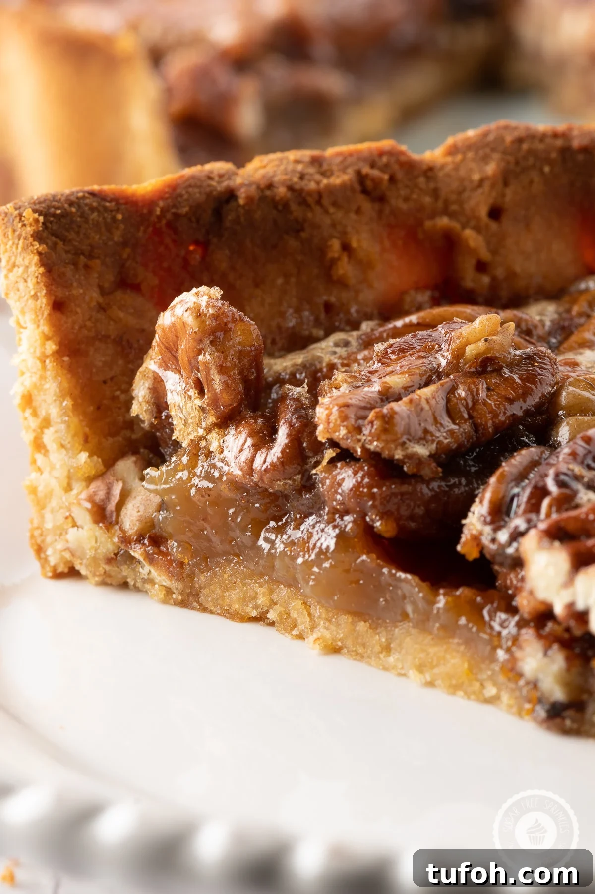 Close up image of a slice of pecan pie with sticky glazed pecans and gooey caramel like filling 