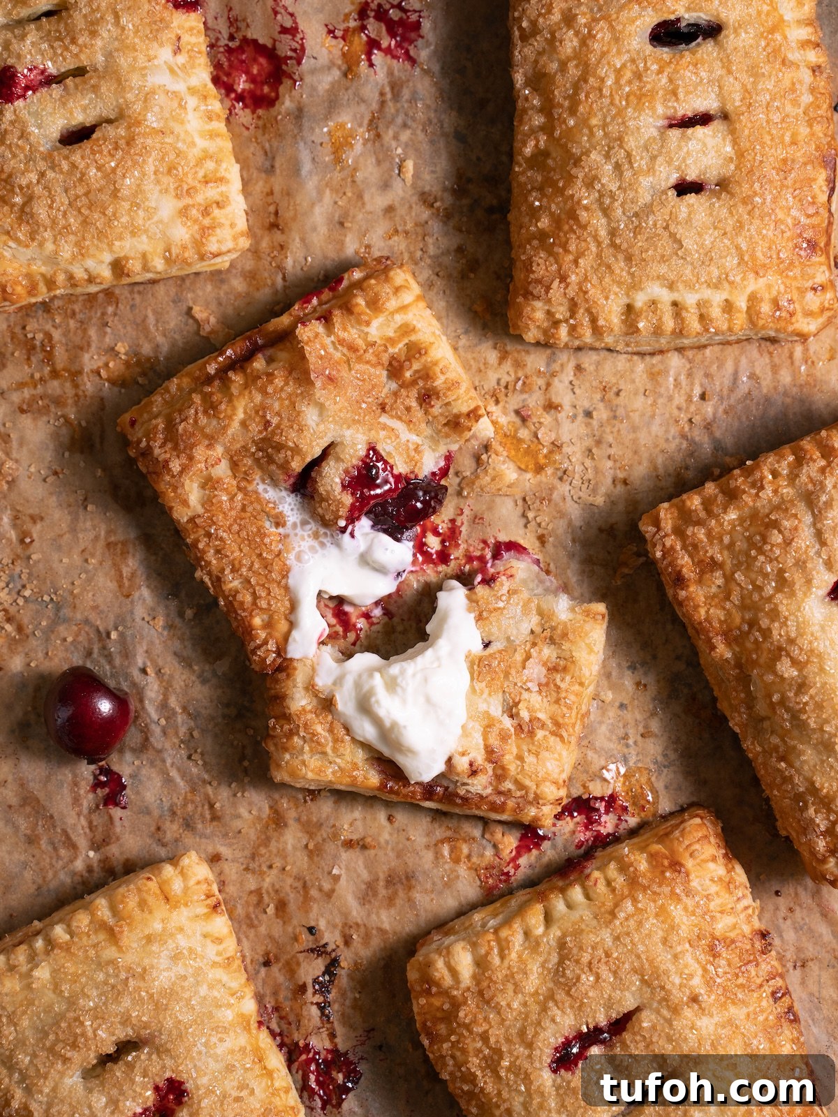 Freshly baked cherry hand pies, with one pie broken open to show filling