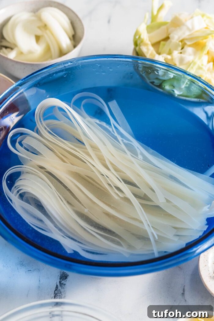 Vegan Drunken Noodles Recipe — Spicy Thai Stir-Fry 4 Wide rice noodles soaking in a large glass bowl.