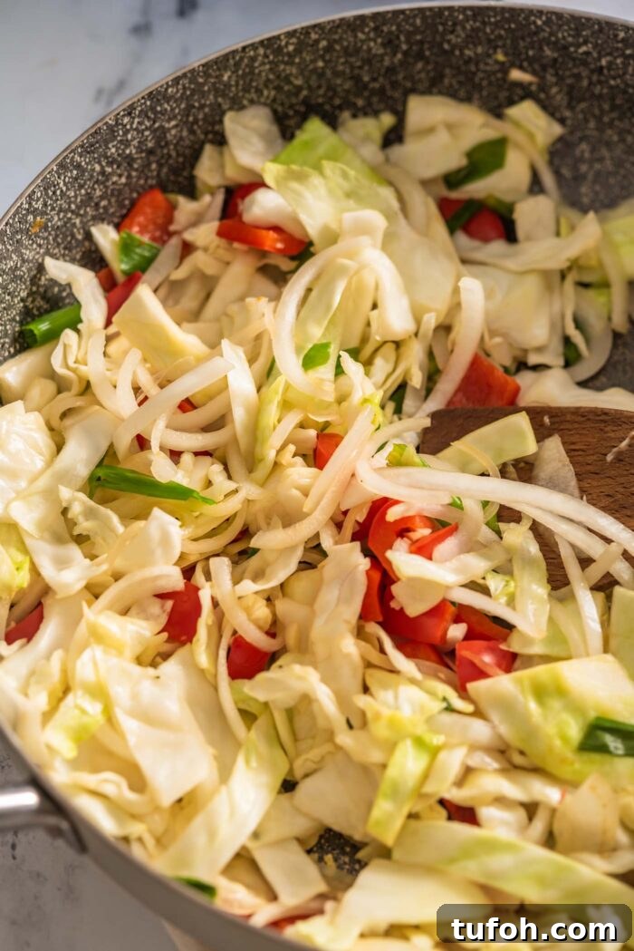 Vegan Drunken Noodles Recipe — Spicy Thai Stir-Fry 7 Cabbage, bell pepper, onion and green onion cooking in a large pan.