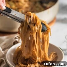 Vegan Drunken Noodles Recipe — Spicy Thai Stir-Fry 10 Using tongs to scoop a serving of Thai drunken noodles into a bowl.