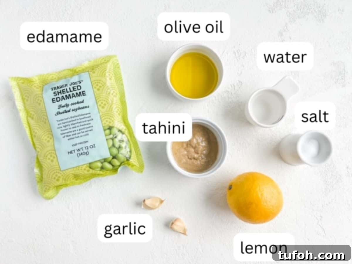 Edamame Hummus Recipe: Creamy, Protein-Packed Dip 3 One bag of shelled edamame, one lemon, two cloves of garlic, and olive oil, water, tahini, and salt in individual small white serving dishes, labeled.