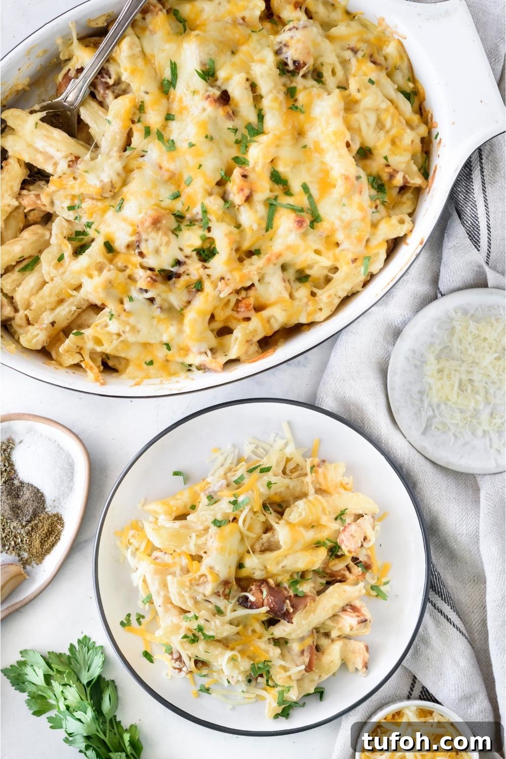 A plate with a portion of chicken alfredo casserole. A casserole dish with the remaining casserole is next to the plate.