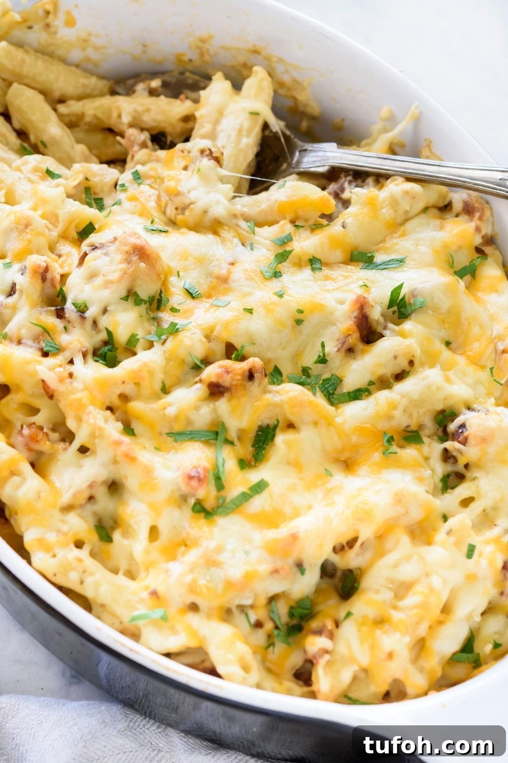 A casserole dish with chicken alfredo bake garnished with parsley.