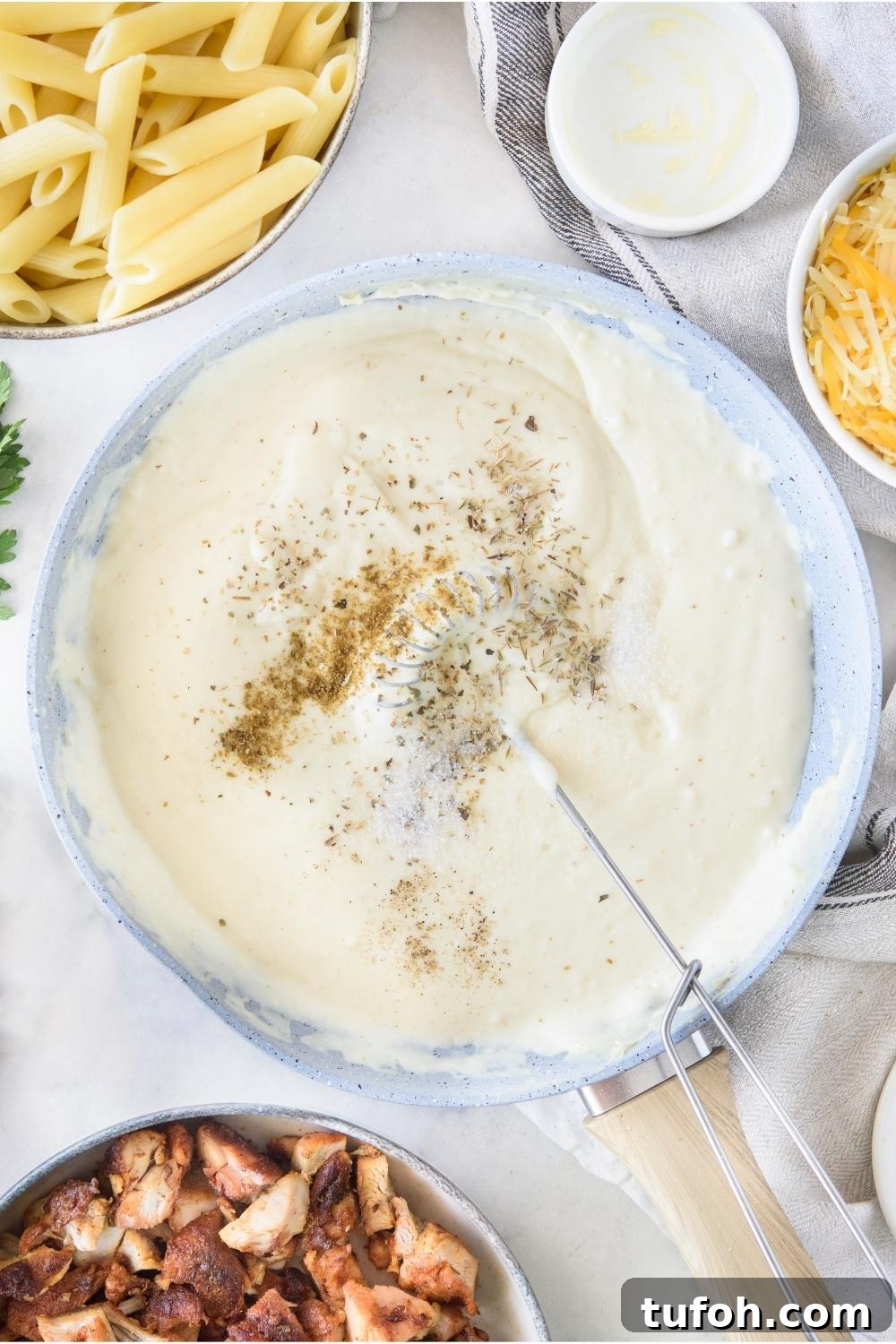 A skillet with alfredo sauce and seasonings being added to it.