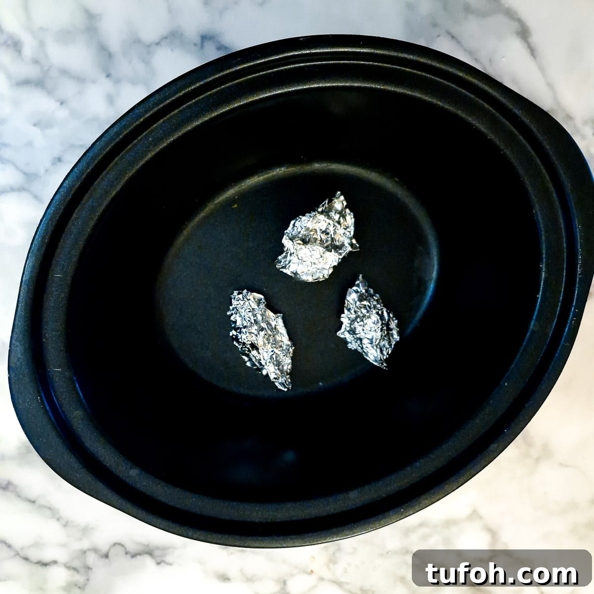Slow-Cooked Curried Leg of Lamb in Foil for Tender Flavor 9 Three small balls of tin foil on the base of a slow cooker.