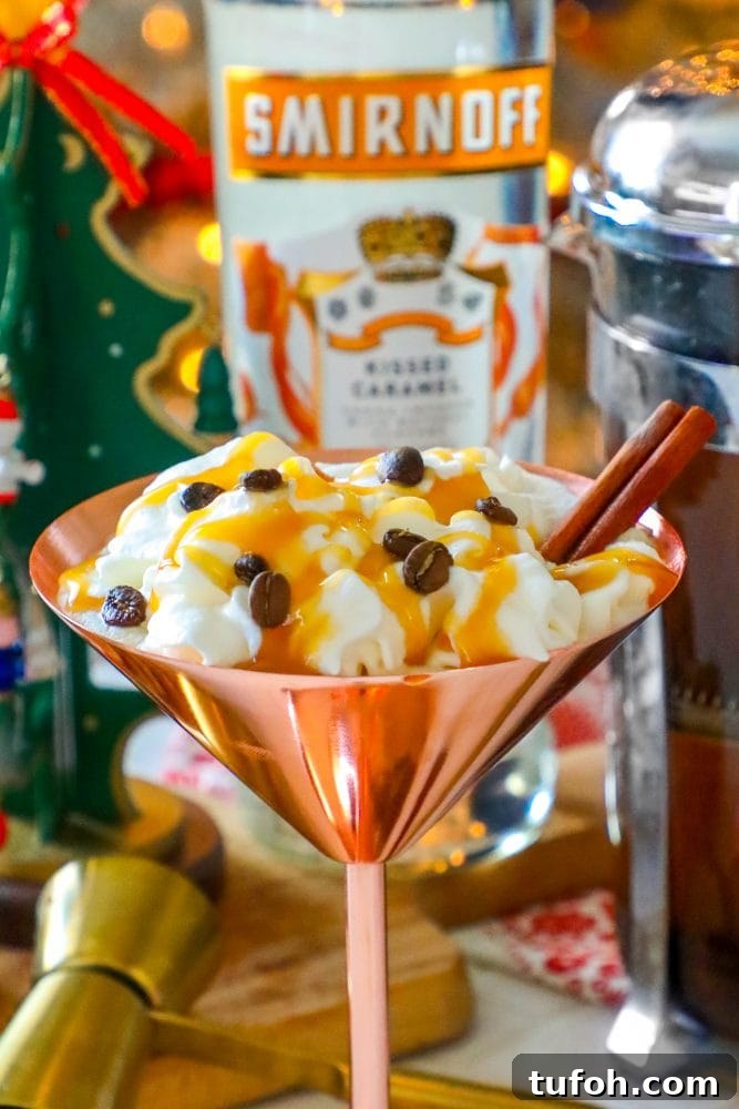 brass martini glass with cream, espresso beans, and cinnamon stick sticking out, Smirnoff in the background
