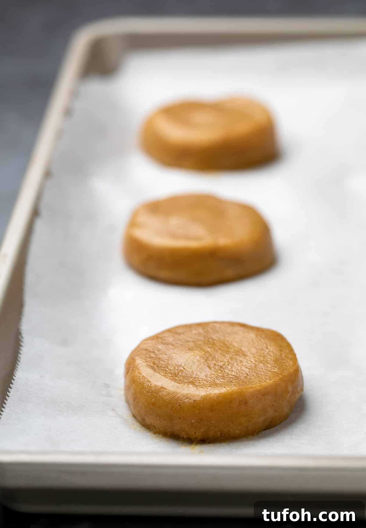 Gluten-Free Pumpkin Cookie Recipe: Soft, Chewy Fall Treat 5 3 disks of raw pumpkin cookie batter on white paper on tray.