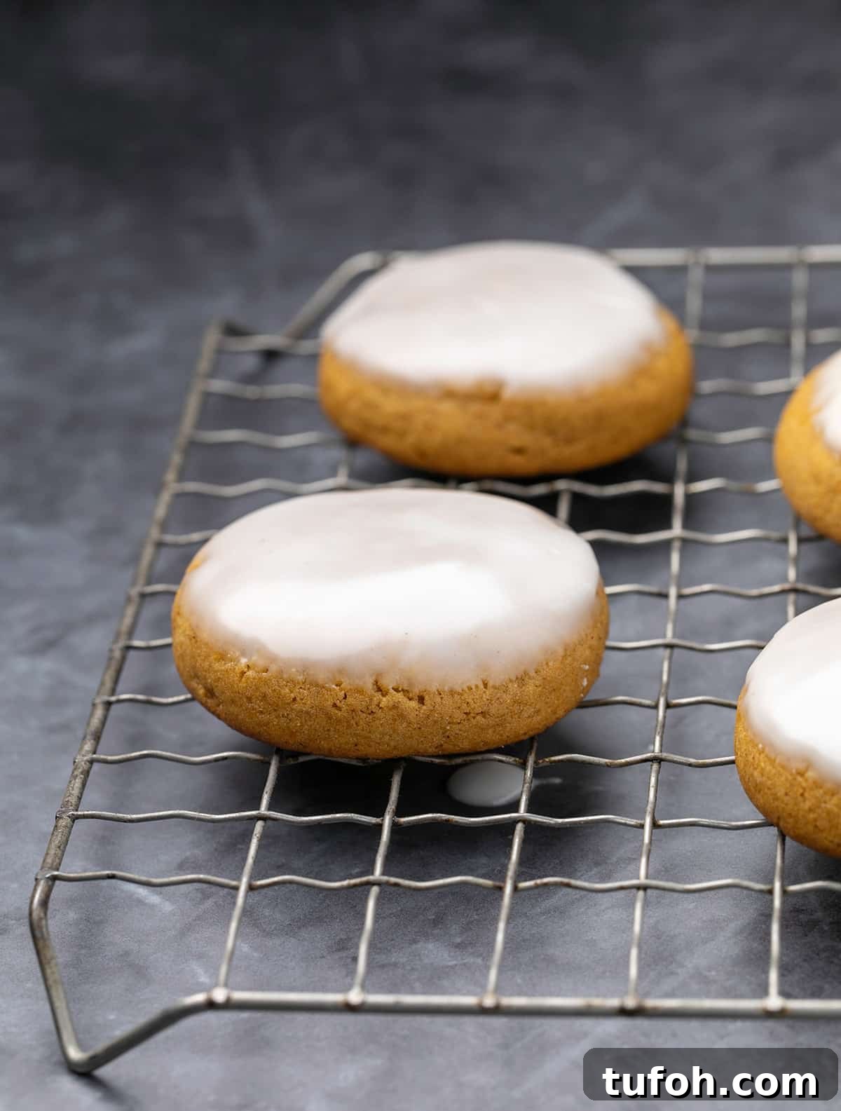 Gluten-Free Pumpkin Cookie Recipe: Soft, Chewy Fall Treat 6 Pumpkin cookies with white icing dripping on wire rack.