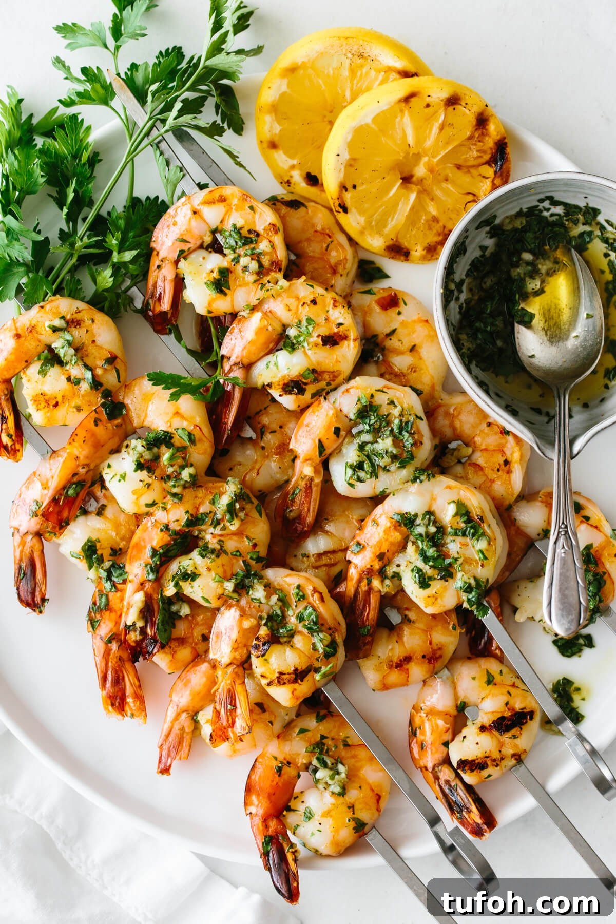 25+ Memorial Day Recipes for Grilling, Picnics & Desserts 2 Grilled shrimp skewers on a plate with lemon slices, parsley and the marinade.
