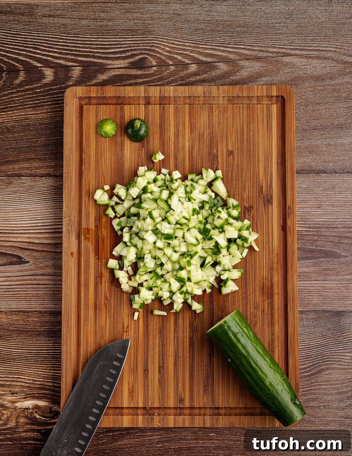 Tangy Pineapple Mango Salsa Recipe for Grilled Fish & Tacos 7 diced cucumber on a cutting board.