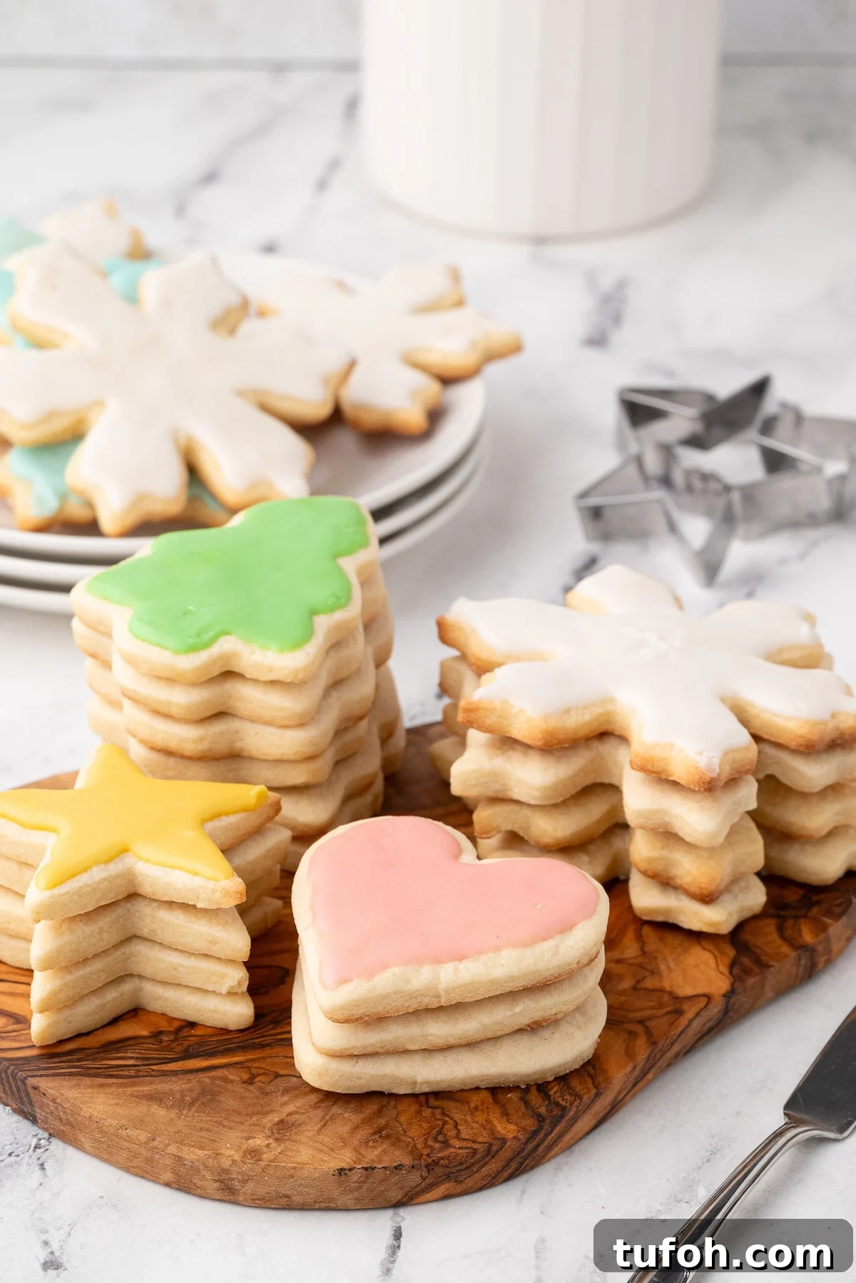 Soft Cut-Out Sugar Cookies Recipe for Tender, Perfect Shapes 3 Stacks of frosted Christmas cookies in light colors.