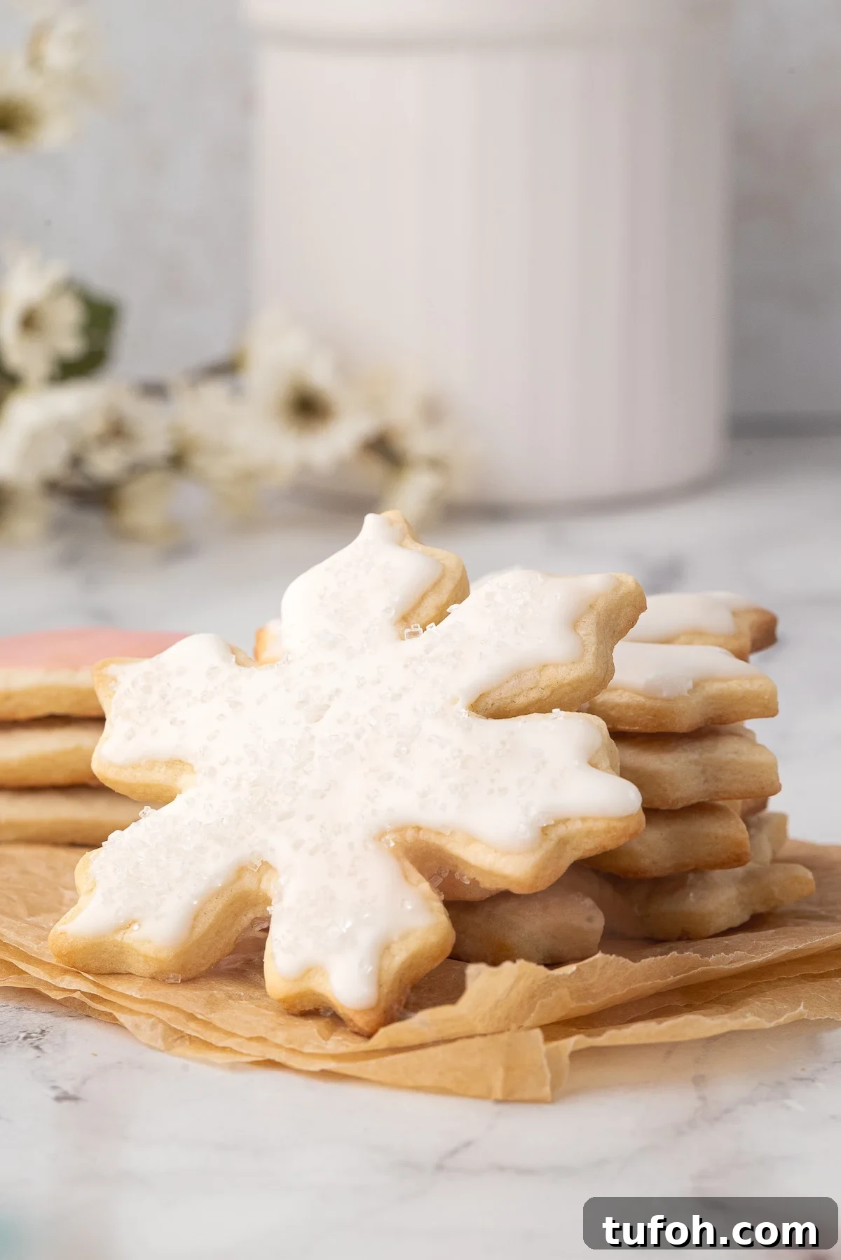Soft Cut-Out Sugar Cookies Recipe for Tender, Perfect Shapes 5 Frosted snowflake sugar cookie with white icing and sugar sprinkles.